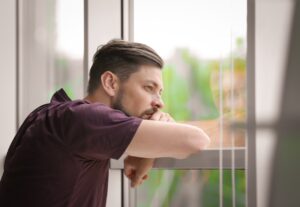 Man looking out window as - visual example of porn addiction symptoms.